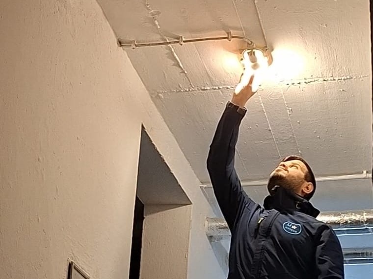 Mitarbeiter von Althamer Haus & Service wechselt ein Leuchtmittel im Treppenhaus
