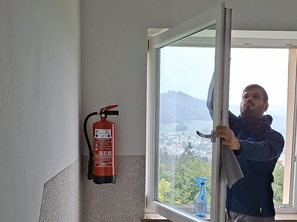 Mitarbeiter von Althamer Haus & Service reinigt ein Fenster mit Blick ins Grüne